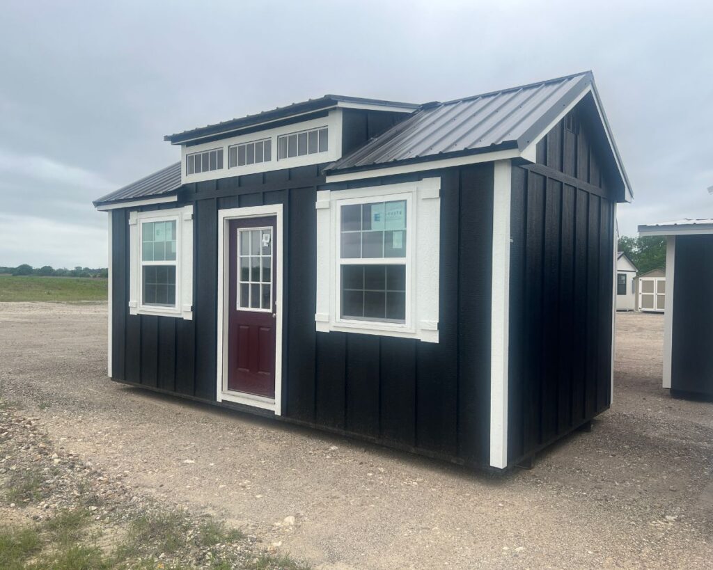 black chalet shed with dormer and burgundy colored door