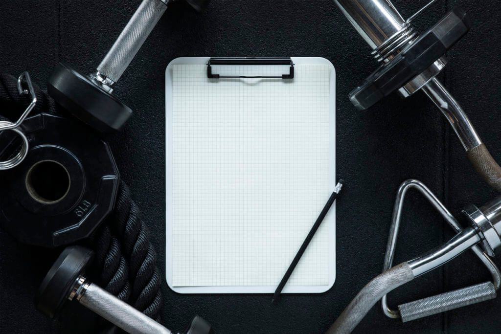 Gym equipment with clipboard and pencil, illustrating the importance of tracking progress